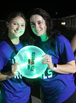 two students holding glowing frisbee