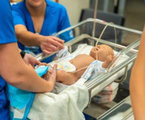 Three LRSC nursing students work on an infant mannequin in lab