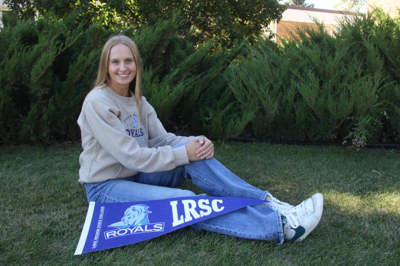 LRSC graduate Kassidy Hart poses on lawn with LRSC pennant